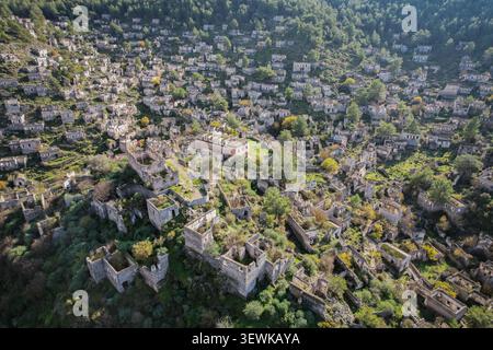 Une vue aérienne montre les maisons en pierre désertes de Kayaköy, un ancien village grec près de Fethiye, en Turquie, situé sur une colline verdoyante sous un ciel ensoleillé Banque D'Images