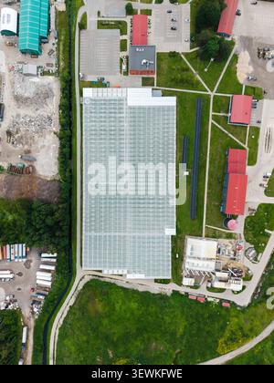 Rumbula, Lettonie - 24 juin 2026 : vue aérienne de la serre Getlini EKO entourée de bâtiments industriels, de champs verts et de parkings Banque D'Images