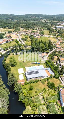 Vue aérienne mettant en évidence une installation sportive communautaire avec piscines et panneaux solaires à côté d'une rivière à Allariz, Galice, Espagne Banque D'Images