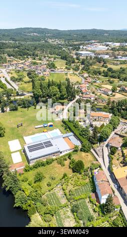 Zone de la ville d'Allariz avec des bâtiments, des panneaux solaires sur un complexe sportif, des piscines, une rivière, un paysage verdoyant et les infrastructures environnantes Banque D'Images