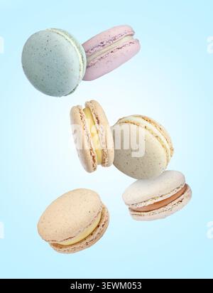 Macarons doux délicieux tombant sur fond bleu clair Banque D'Images