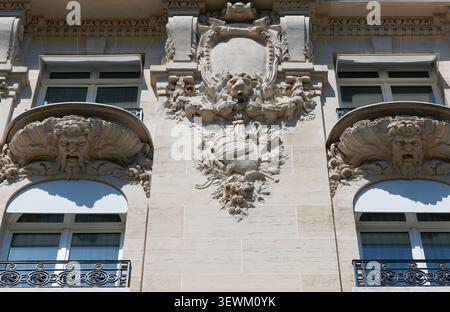 Détail architectural saisissant sur les champs-Élysées, Paris, avec deux mascarons en pierre grimacante soutenant des balcons ornés. Banque D'Images