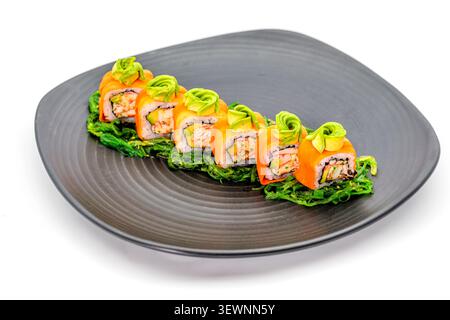 Petits pains de sushi gourmands recouverts d'avocat et de saumon servis sur une élégante assiette sombre isolée sur fond blanc Banque D'Images