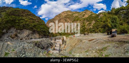 Chantier de construction d’une petite centrale hydroélectrique (mini centrale hydroélectrique) dans une vallée de montagne rocheuse avec des structures et des équipements en béton. Banque D'Images