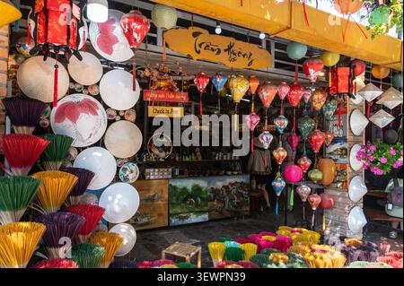 Une façade de magasin ouverte avec un affichage complet de chapeaux coniques, des bouquets de bâtons de joss colorés et des lanternes suspendues en vente dans Huyen Tran Cong Chua Street, Banque D'Images