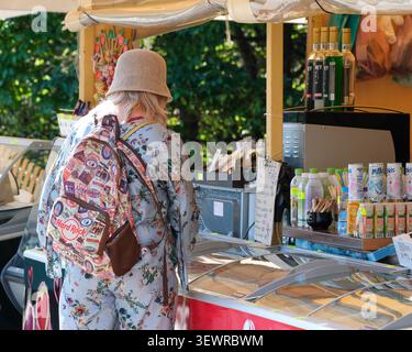 KIEV, UKRAINE - 28 JUIN 2026 : vue arrière d'une femme portant un sac à dos alors qu'elle achetait des boissons et des collations dans un kiosque de rafraîchissements à M. M. Gryshko National Banque D'Images