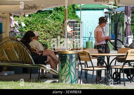 KIEV, UKRAINE - 28 JUIN 2026 : visiteurs se relaxant dans un café en plein air dans le jardin botanique national M. M. Gryshko par une journée d'été ensoleillée, avec des gens assis Banque D'Images