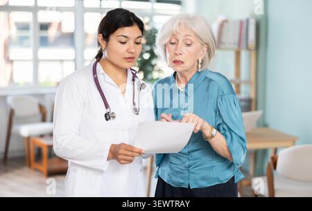 Triste patient de femme senior avec des documents discutent du traitement avec le médecin féminin latin Banque D'Images