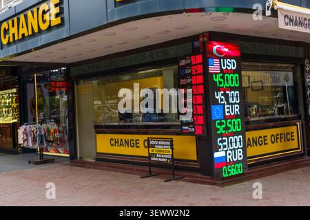 Bureau de change dispose d'un affichage numérique des taux de change pour USD, EUR et RUB, situé dans une zone commerciale animée avec des magasins à proximité Banque D'Images