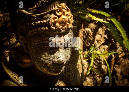 Statue spirituelle balinaise de Dewi Sri présentant des détails de sculpture complexes, reflétant la culture et le patrimoine anciens, debout dans un jardin tropical paisible avec une lumière naturelle et une verdure environnante Banque D'Images