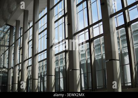 Intérieur d'architecture moderne avec de grands murs de façade en verre avec structure en acier et ombres géométriques du soleil dans un bâtiment terminal lumineux. Banque D'Images