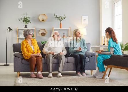 Groupe de personnes âgées assis sur le canapé en maison de retraite avec une jeune infirmière. Banque D'Images
