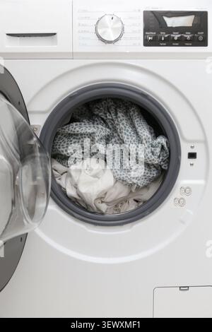 Gros plan du tambour de machine à laver ouvert avec le linge à l'intérieur, concept de nettoyage ménager Banque D'Images