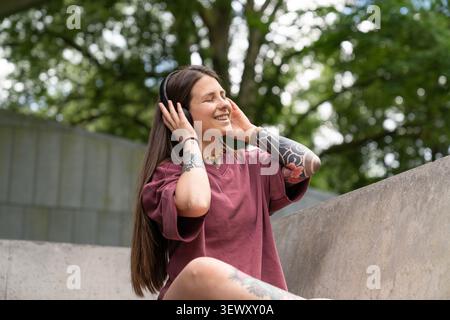 Jeune femme profitant de la musique avec des écouteurs en plein air souriant Banque D'Images