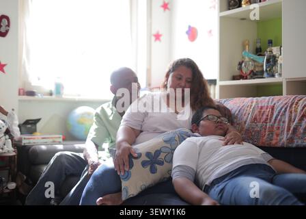 Les parents regardant leur fils sieste sur le canapé Banque D'Images