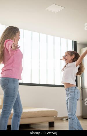 Heureuse mère et fille jouant ensemble les bras levés à la maison Banque D'Images