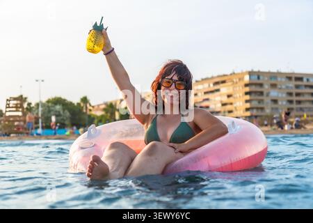 Jeune femme profitant des vacances d'été flottant dans la mer Banque D'Images