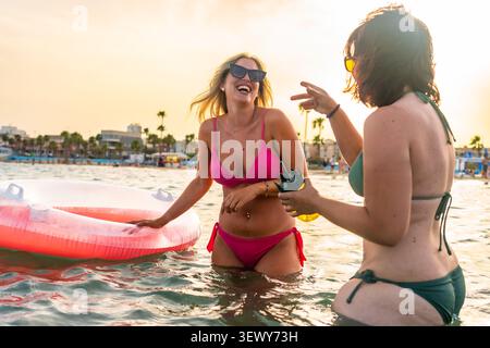 Amis profitant de vacances d'été sur la plage au coucher du soleil Banque D'Images