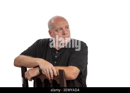Homme chauve-souris lourd d'âge moyen assis à l'arrière sur une chaise en bois dans le portrait de studio, expression réfléchie, fond blanc, composition isolée Banque D'Images