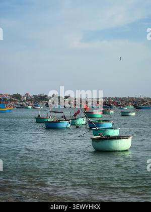 Bateaux ronds traditionnels vietnamiens sur la mer. Des bateaux à panier tissés ronds colorés ancrés dans les eaux turquoises calmes d'un village de pêcheurs. Banque D'Images