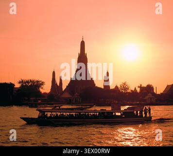 Thaïlande. Bangkok. Wat Arun. Vue sur les bâtiments du temple de l'autre côté de la rivière Chao Phraya au coucher du soleil. Banque D'Images