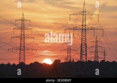 Poteaux électriques devant un coucher de soleil intense, le ciel est rouge et le paysage floue en silhouettes, Bade-Wuerttemberg, Allemagne Banque D'Images