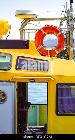 Extérieur de bateau jaune avec bouée de sauvetage et porte ouverte montrant l'intérieur avec une chaise Banque D'Images