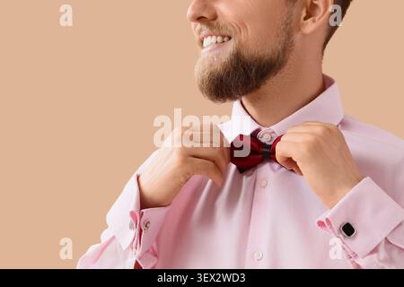 Homme ajustant le noeud papillon rouge sur chemise rose Banque D'Images