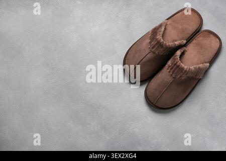 Paire de chaussons confortables marron sur la surface grise Banque D'Images
