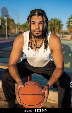 Jeune athlète masculin tenant des matchs de basket-ball sur un terrain en plein air Banque D'Images