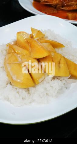 Gros plan vertical assiette en céramique blanche à la mangue thaïlandaise riz collant doux traditionnel dessert Banque D'Images