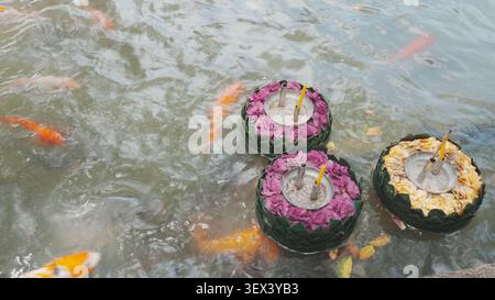 Vue de dessus trois krathong fleuris ornés flottant sur la surface de l'eau tranquille de Garden Pond Banque D'Images