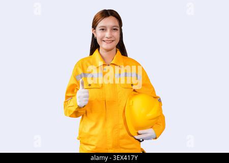 Beau modèle de femme ingénieur, femme ouvrière heureuse souriant dans le costume de sécurité pouces vers le haut isolé sur blanc dans le studio. Banque D'Images