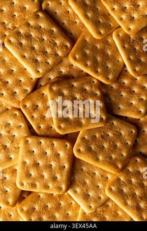 Vue macro rapprochée d'une pile de craquelins carrés dorés avec une mise au point peu profonde et une texture croquante chaude Banque D'Images
