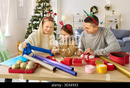 Cadeau d'emballage de famille de Noël avec l'aide de l'enfant, parent et fille décorer des boîtes Banque D'Images
