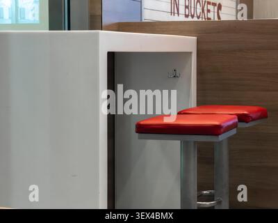 La station-service moderne dispose d'un haut comptoir blanc et de sièges rouges rembourrés contre un mur en bois chaleureux, créant un espace fonctionnel simple pour un efficient Banque D'Images