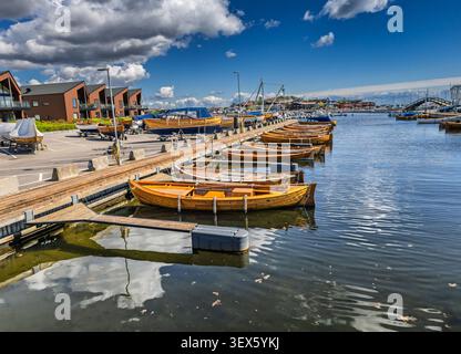 Vue aérienne de petits bateaux en bois amarrés dans un port paisible sous un ciel bleu vif avec des nuages dispersés. Banque D'Images