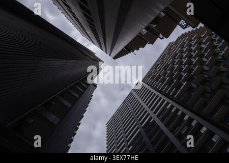 Gratte-ciel urbain moderne s'étendant haut dans un ciel nuageux dramatique, créant un sentiment d'échelle imposante et l'architecture de la ville contemporaine d'un bas Banque D'Images
