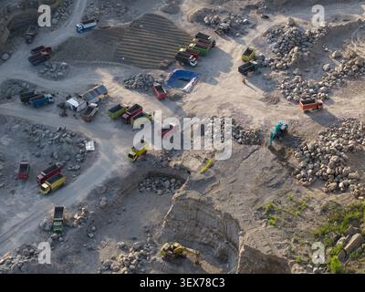 Vue aérienne de la carrière de sable et de pierre avec plusieurs camions à benne basculante, des excavatrices et des tas de roches dans le paysage industriel de Manisrenggo, Central Banque D'Images