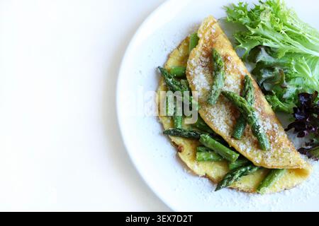 Asperges maison et omelette parmesan servie avec salade verte fraîche sur une assiette blanche. Vue de dessus. Banque D'Images