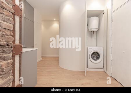 Petit appartement moderne avec une armoire intégrée contenant un lave-linge et un chauffe-eau électrique. Banque D'Images