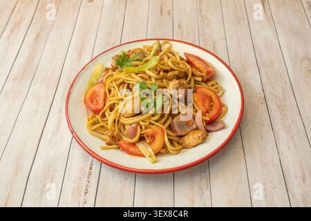 Nouilles péruviennes sautées avec du bœuf juteux, nouilles épaisses sautées dans un wok avec oignon, tomate, poivrons rouges et jaunes Banque D'Images