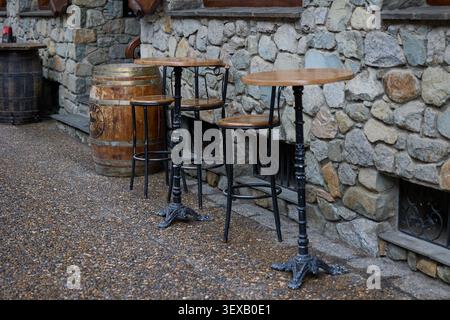 Grandes tables et tabourets de bar dans la rue de la vieille ville en face du café. Banque D'Images