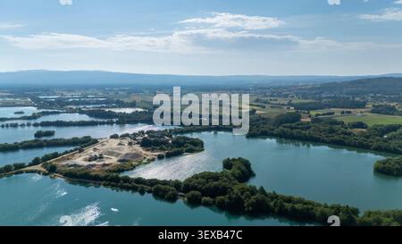 Vue aérienne d'une carrière de sable et de gravier avec de multiples étangs industriels et une végétation verte, s'étendant dans les champs agricoles Banque D'Images