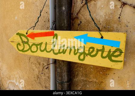 Panneau de boulangerie peint à la main avec des flèches colorées sur un mur délavé en Provence, France Banque D'Images