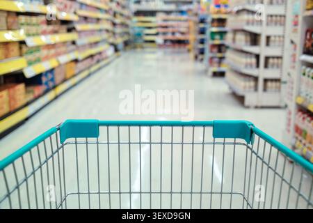 Gros plan de panier vide dans une épicerie avec des étagères de supermarché flues, des allées de produits Banque D'Images