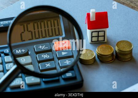 Calcul du coût hypothécaire avec calculatrice, loupe, modèle de maison et économies de pièces pour les acheteurs de maison Banque D'Images