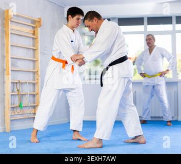 Maître de jiu-jitsu démontrant des grappins et des lancers de base en sparring avec un jeune combattant Banque D'Images
