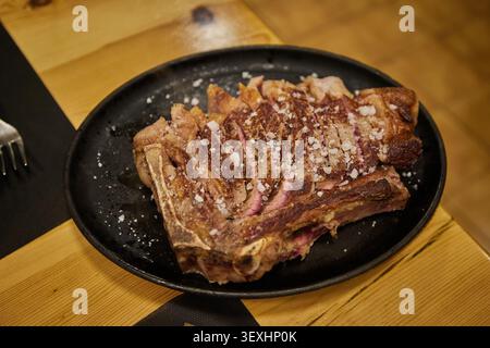Steak espagnol traditionnel côtelé sur l'os Chuleton, cuit sur charbon de bois et tranché à partager, servi dans un restaurant. Banque D'Images