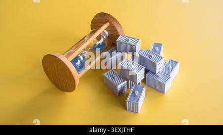 Angle élevé de sablier en bois se trouvant à côté de la pile de conteneurs de cargaison miniature concept de retard logistique sur fond jaune Banque D'Images